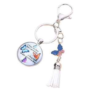 Silver butterfly keychain with white tassel and glass pendant featuring inspirational quote