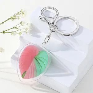 Detailed close-up of acrylic heart-shaped leaf keychain with pink and green texture