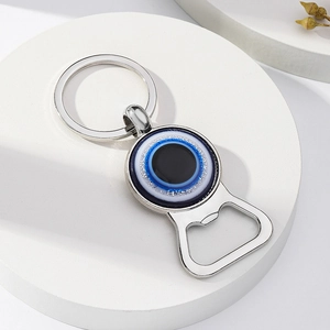 Porte-clés décapsuleur en métal argenté avec œil bleu sur support blanc élégant