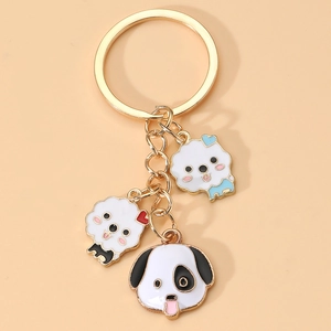 Cute Korean style golden keychain with three enamel cartoon dog pendants on pink background