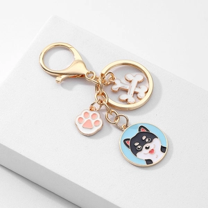 Détail d'un porte-clés doré pour chien avec breloque patte et pendentif chiot en émail