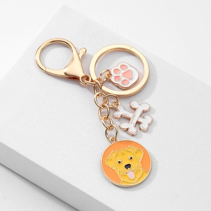 Détails d'un porte-clés doré pour chien avec breloques de patte, os et portrait de golden retriever