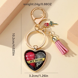 Détail d'un porte-clés coeur doré avec breloque rose rouge et pompon décoratif en cuir rose