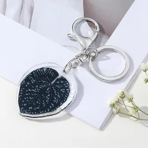 Detailed close-up of leaf pattern acrylic keychain with silver metal clasp on white background