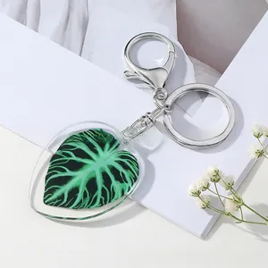 Detailed close-up of a heart-shaped acrylic keychain featuring a green leaf vein pattern