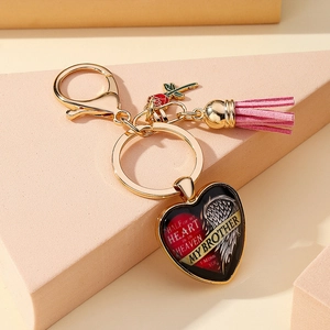 Vue détaillée du porte-clés commémoratif cœur avec pompon rose et mousqueton doré brillant