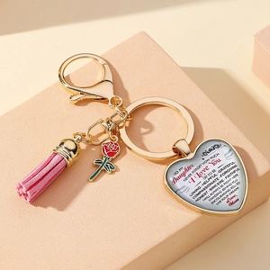 Detail of heart pendant keychain with pink tassel, rose charm and inspiring words for daughter