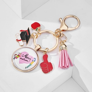 Close-up of golden graduation keychain with Merci Maitresse pendant and pink leather tassel