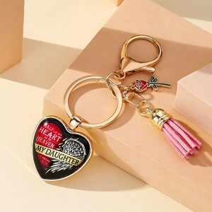 Détail d'un porte-clés commémoratif en cœur avec rose rouge et pompon rose