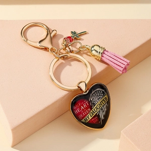 Détail macro d'un porte-clés cœur doré avec un gland rose et une gravure commémorative