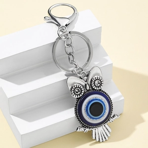 Detail view of owl keychain with blue evil eye enamel charms on white display