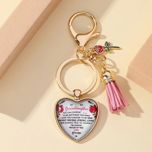 Golden heart keychain with pink tassel and rose charm featuring inspirational quote