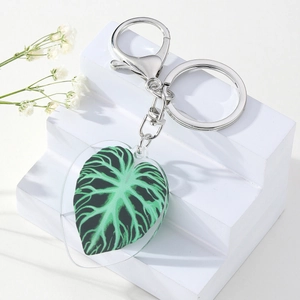 Tropical heart-shaped acrylic leaf keychain with silver horseshoe clasp on white decor