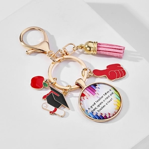 Detail of graduation keychain with pink tassel, red apple charm and teacher quote pendant