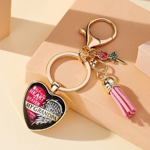 Détail d'un porte-clés commémoratif en forme de cœur doré avec rose et pompon rose