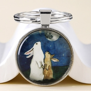 Vue détaillée du porte-clés en métal avec deux lapins et lune sous dôme en verre clair