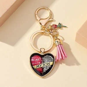 Porte-clés cœur doré avec rose et texte commémoratif sur fond géométrique chaleureux