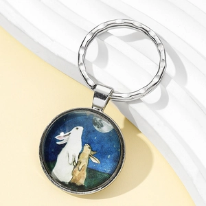 Vue rapprochée du pendentif lapin et lune en argent avec cabochon sur fond texturé blanc
