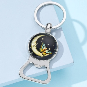 Close-up of moon and butterfly metal bottle opener keychain with celestial illustration