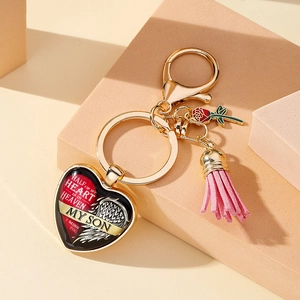 Gros plan d'un porte-clés commémoratif en cœur doré avec pompon rose et rose