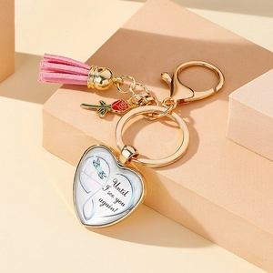 Detail of heart pendant keychain with dragonfly illustration and pink suede tassel