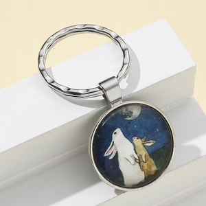 Détail d'un porte-clés vintage en métal avec deux lapins regardant la lune sous verre