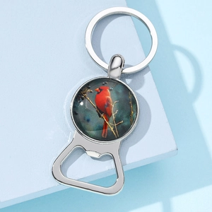 Macro view of silver metal keychain bottle opener featuring a cardinal bird glass pendant