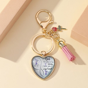 Macro shot of gold heart keychain with pink tassel, red rose charm and memorial quote