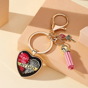Détail d'un porte-clés cœur doré avec breloque rose et pompon rose sur blocs