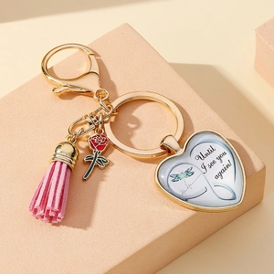Detailed view of heart memorial keychain with red rose, pink tassel, and dragonfly pendant