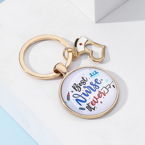 Détail du porte-clés doré Best Nurse Ever avec breloque chapeau d'infirmière et icônes médicales