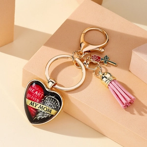 Détail d'un porte-clés cœur avec pompon rose, breloque rose et pendentif commémoratif