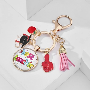 Detailed view of teacher appreciation gold keychain with 'Best Teacher' glass charm and tassels