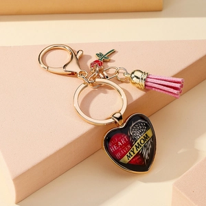 Détail d'un porte-clés commémoratif en forme de cœur avec pompon rose et crochet doré