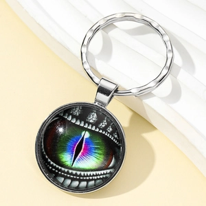 Detail of silver alloy dragon eye keychain with transparent glass dome on light background