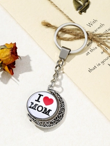 Detail of rotating silver heart pendant with I Love Mom engraving on floral background