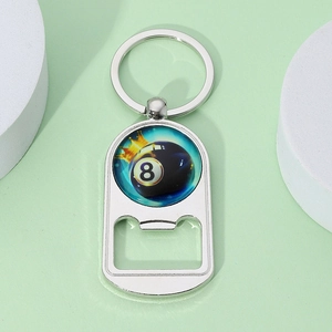 Close-up of a silver 8-ball billiard bottle opener keychain on a light green surface