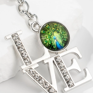 Silver LOVE keychain with peacock feather glass gem and sparkling rhinestones inlay