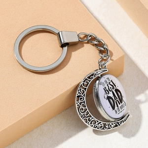 Silver moon-shaped spinning keychain with 'Best Dad' engraving on an orange background