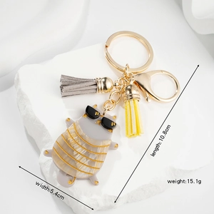 Cute cartoon cat keychain with gray tassel and dimensions 10.8x5.4cm on a white stone base