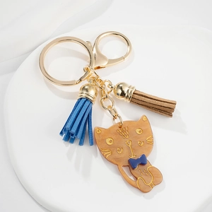 Cute brown acetate cat keychain with blue bow and matching suede tassels on white tray
