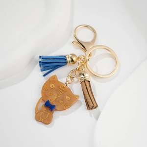 Detail of cute cat pendant with blue bow, suede tassels, and golden keychain hardware