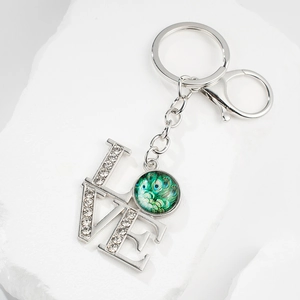 Detailed view of silver metal LOVE keychain with peacock gem and sparkling rhinestones