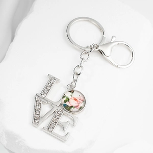 Porte-clés LOVE argenté avec pendentif rose et strass brillants sur fond de pierre