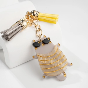 Close-up of cute grey acrylic cat keychain with gold stripes and colorful leather tassels