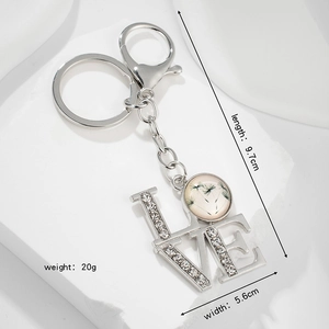 Vintage LOVE keychain with dandelion glass pendant and rhinestones on stone background