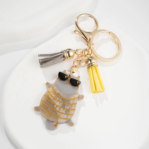 Cute cat keychain with colorful tassels and gold metal clip on minimalist white stand