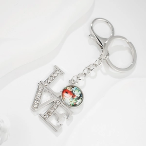 Close-up of LOVE lettering with rhinestones and floral pendant on silver keychain