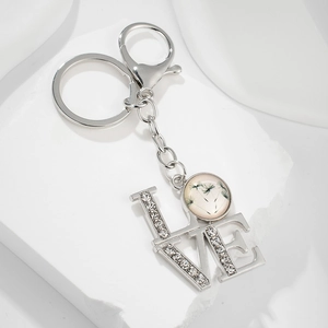 Detailed macro view of silver LOVE keychain with dandelion glass cabochon and rhinestones