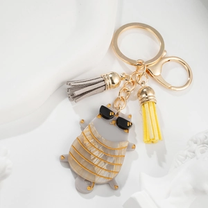 Detailed view of gray cat keychain with black sunglasses and colorful tassels